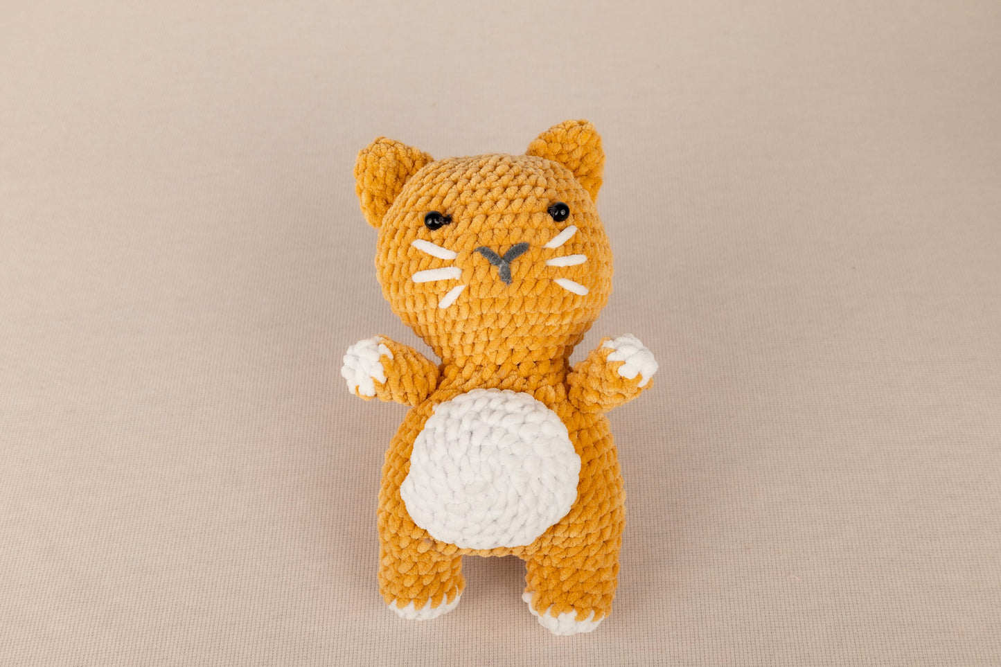 a crocheted orange and white cat sitting on its hind legs