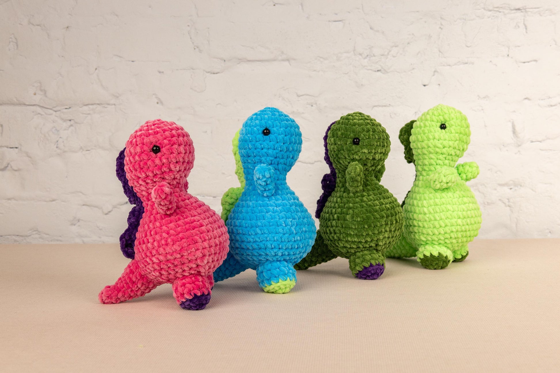 a group of three crocheted dinosaurs sitting next to each other