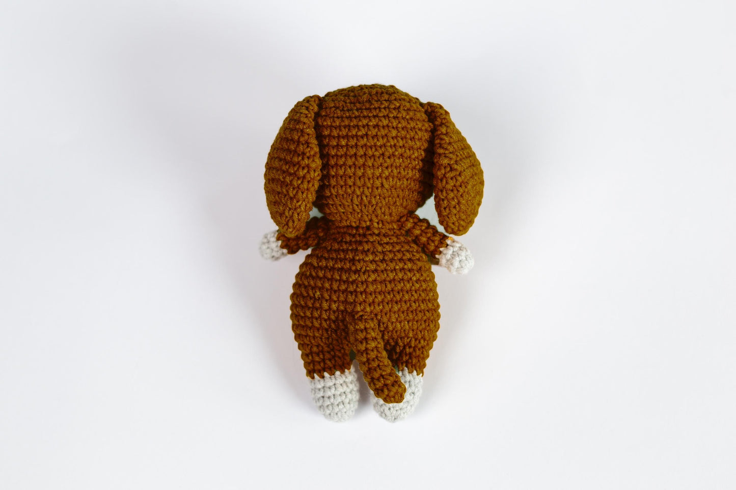 a crocheted dog is laying down on a white surface