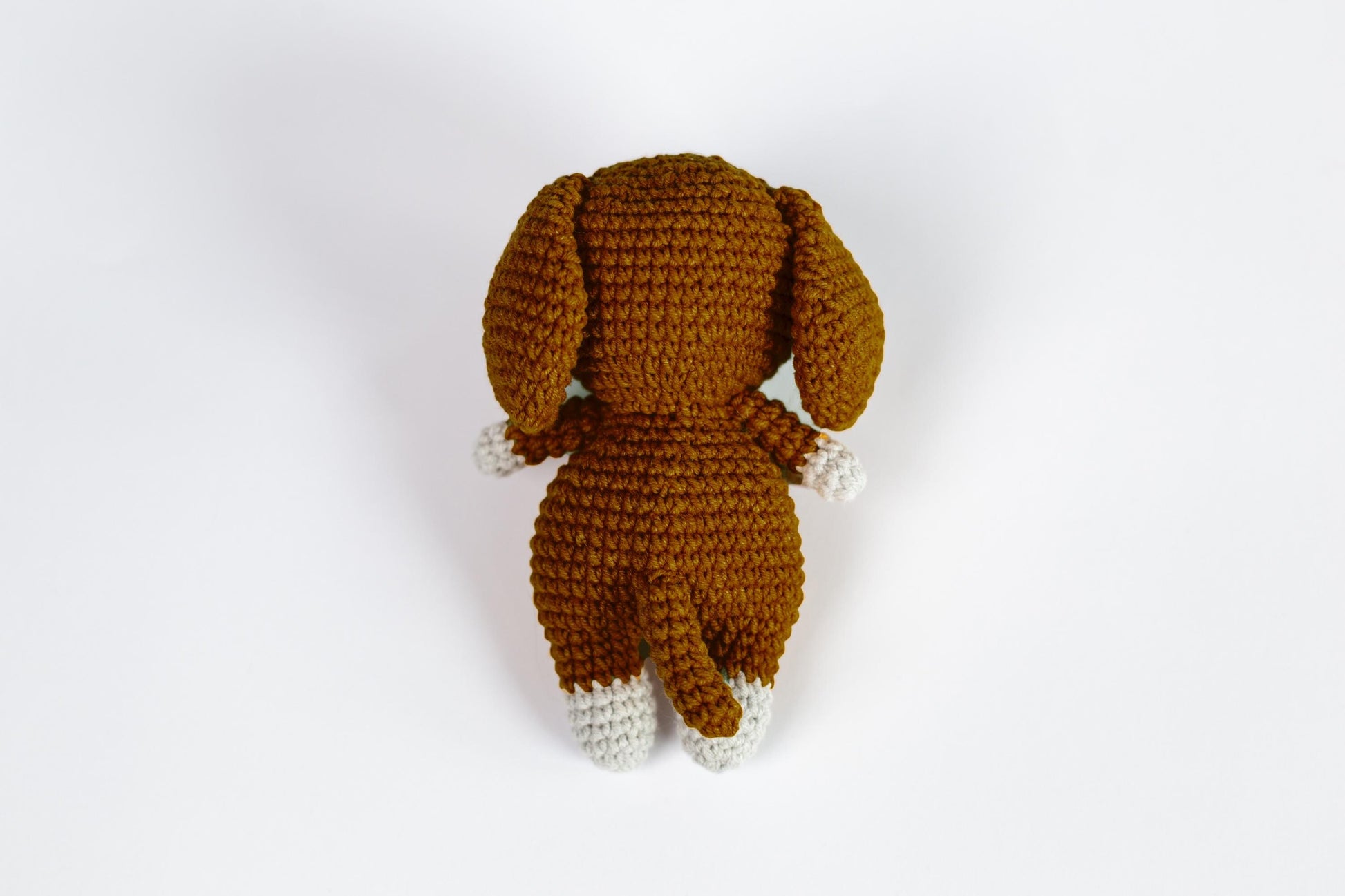 a crocheted dog is laying down on a white surface