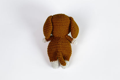 a crocheted dog is laying down on a white surface