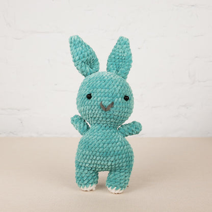 a crocheted blue bunny sitting on top of a table