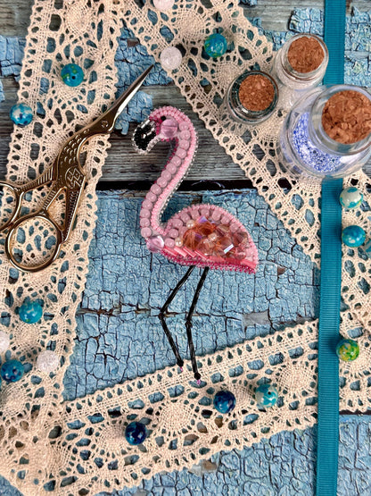 a pink flamingo is sitting on a piece of lace