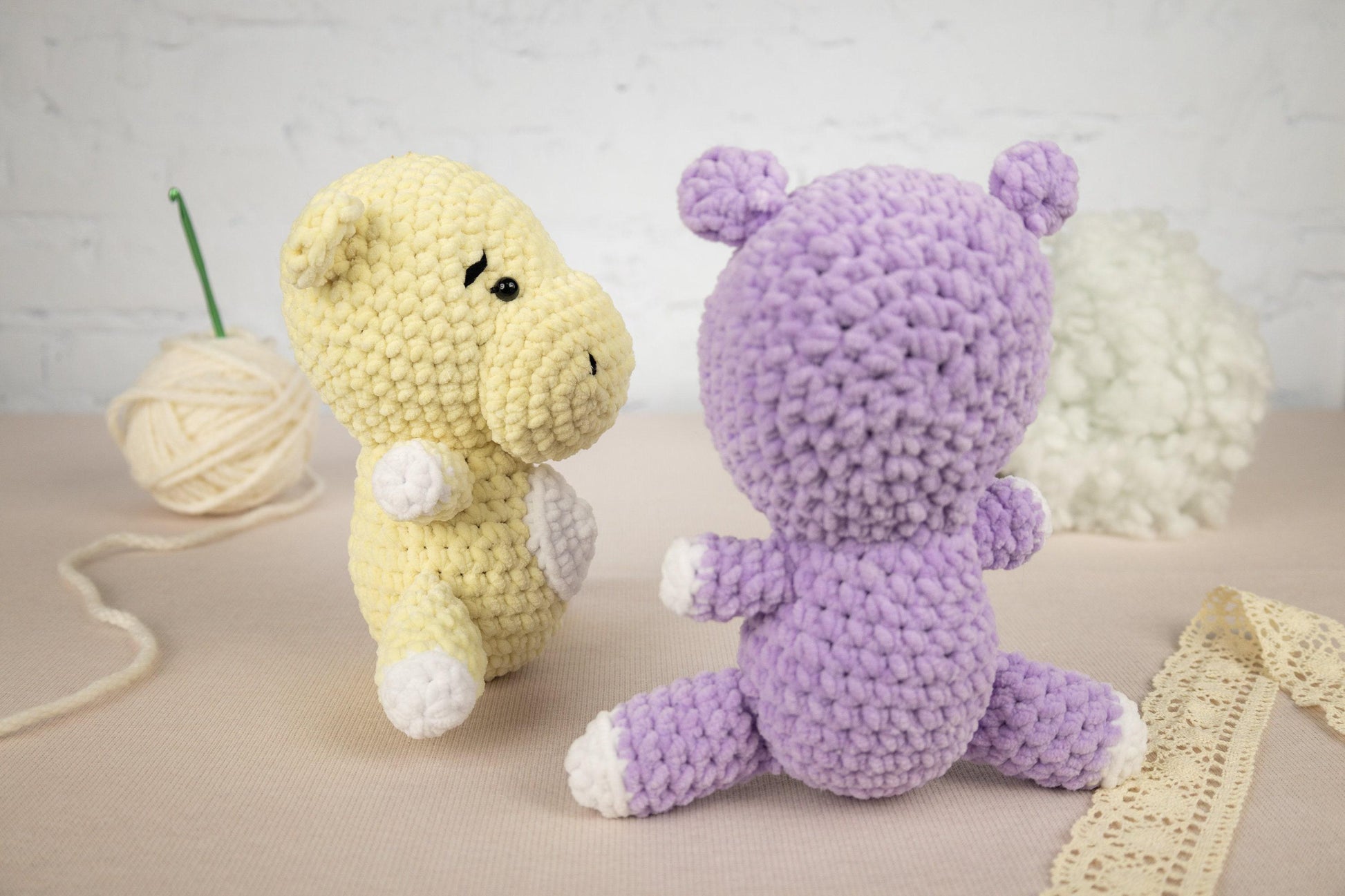 two crocheted stuffed animals sitting next to a ball of yarn