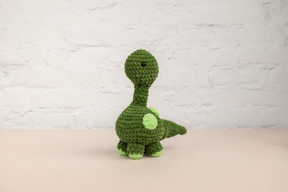 a crocheted green dinosaur sitting on a table