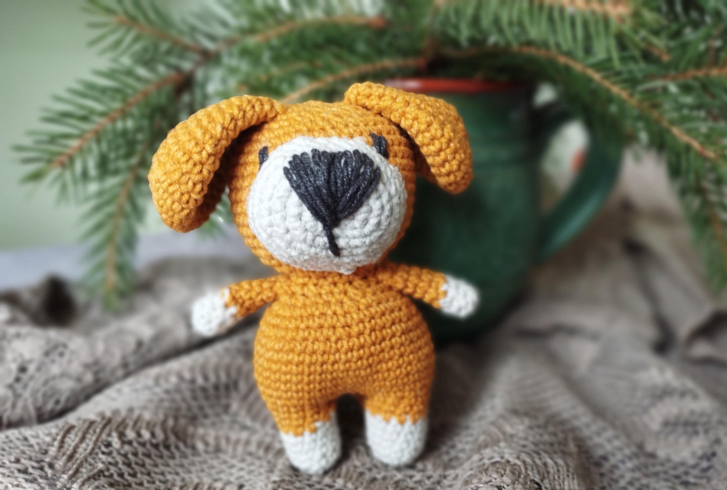 a crocheted dog sitting next to a cup of coffee