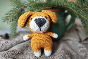 a crocheted dog sitting next to a cup of coffee