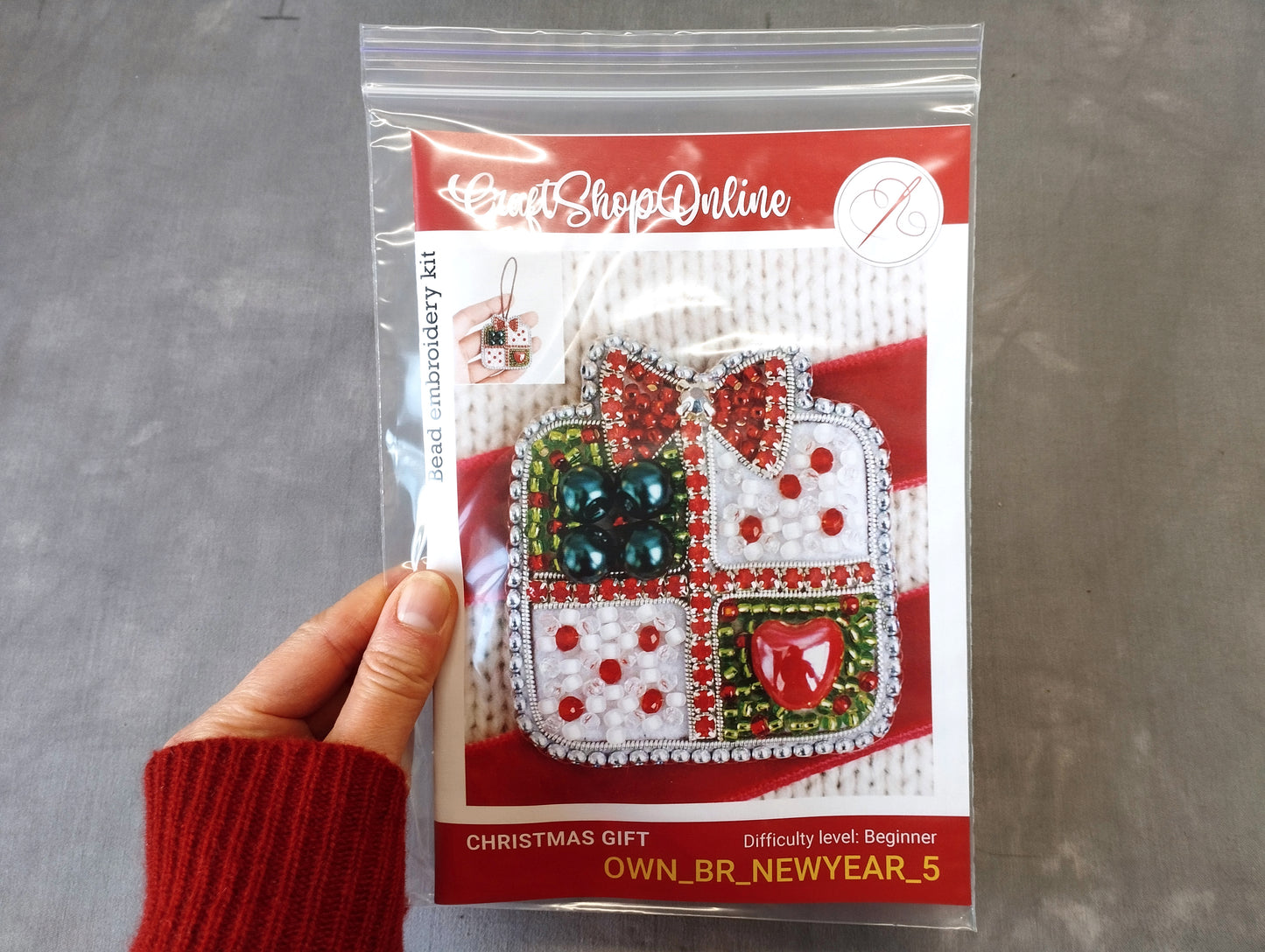 A hand holding a package of a Christmas gift kit, with a picture of the kit on the front.