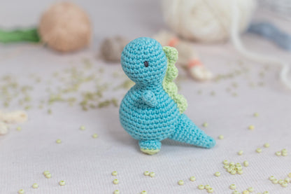 a small crocheted toy of a dinosaur on a table