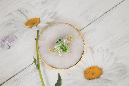 daisies and a brooch sitting on a white wooden surface