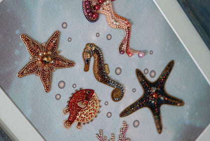 a collection of colorful, intricately designed sea creatures, including a starfish, a seahorse, a fish, and a coral, all adorned with beaded and embroidered embellishments.