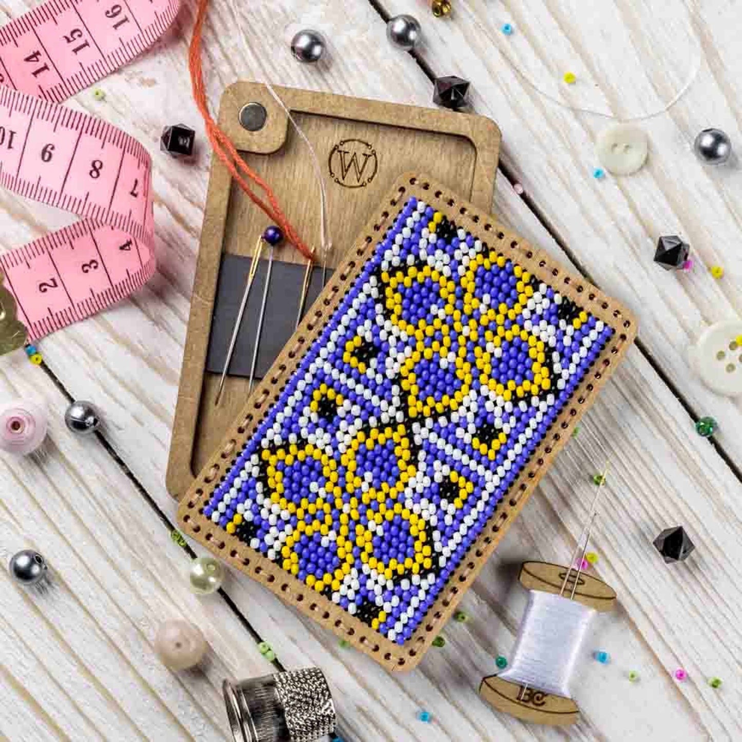 a piece of beaded art next to a measuring tape