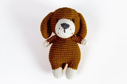 a crocheted brown dog laying down on a white surface