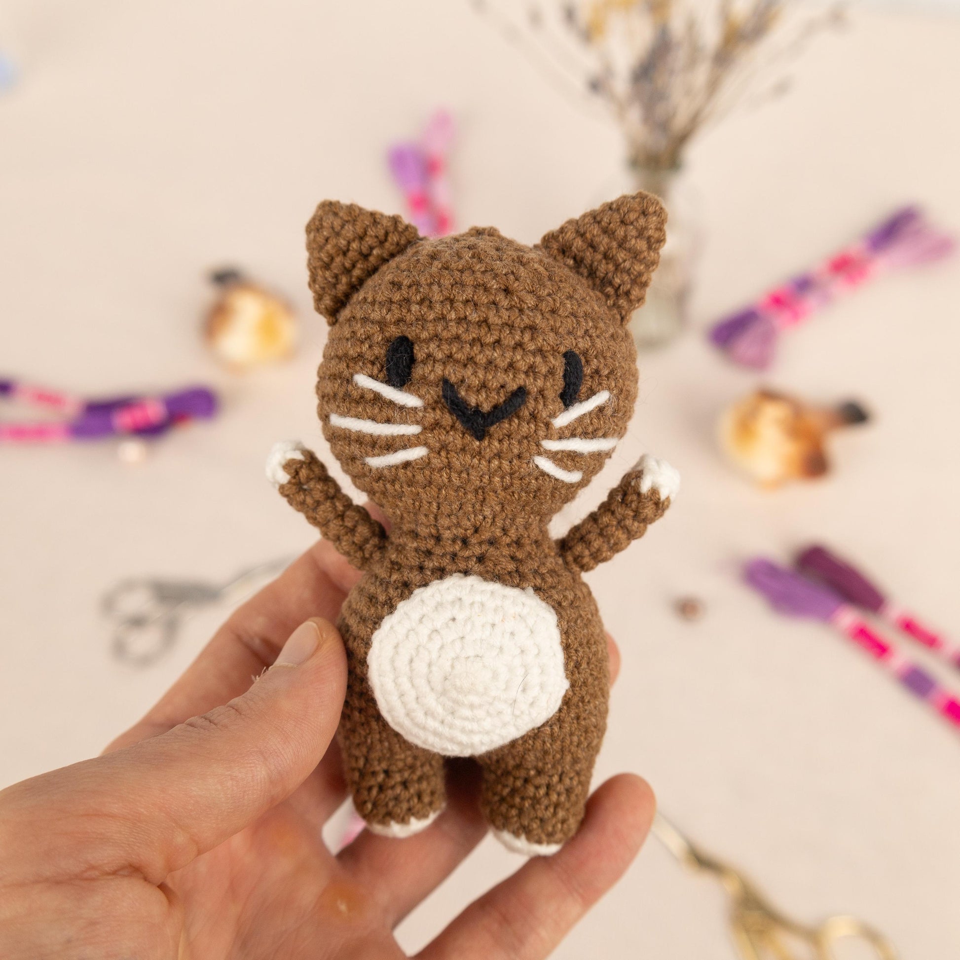 a hand holding a small crocheted cat