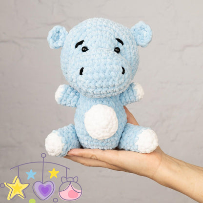 a hand holding a blue crocheted teddy bear