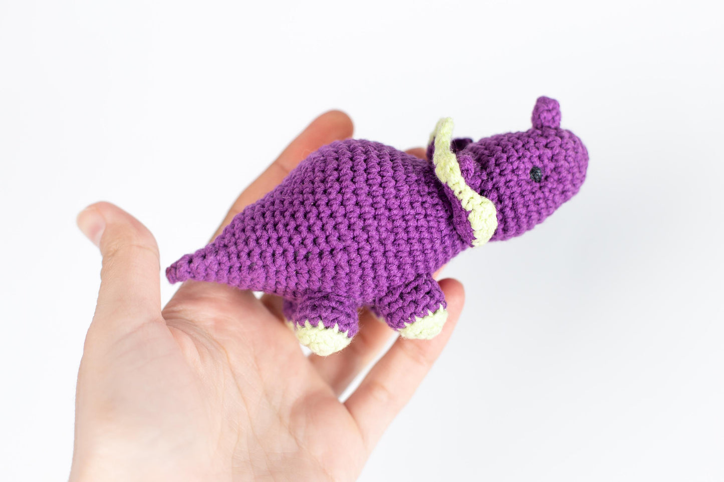 a hand holding a small purple crocheted animal