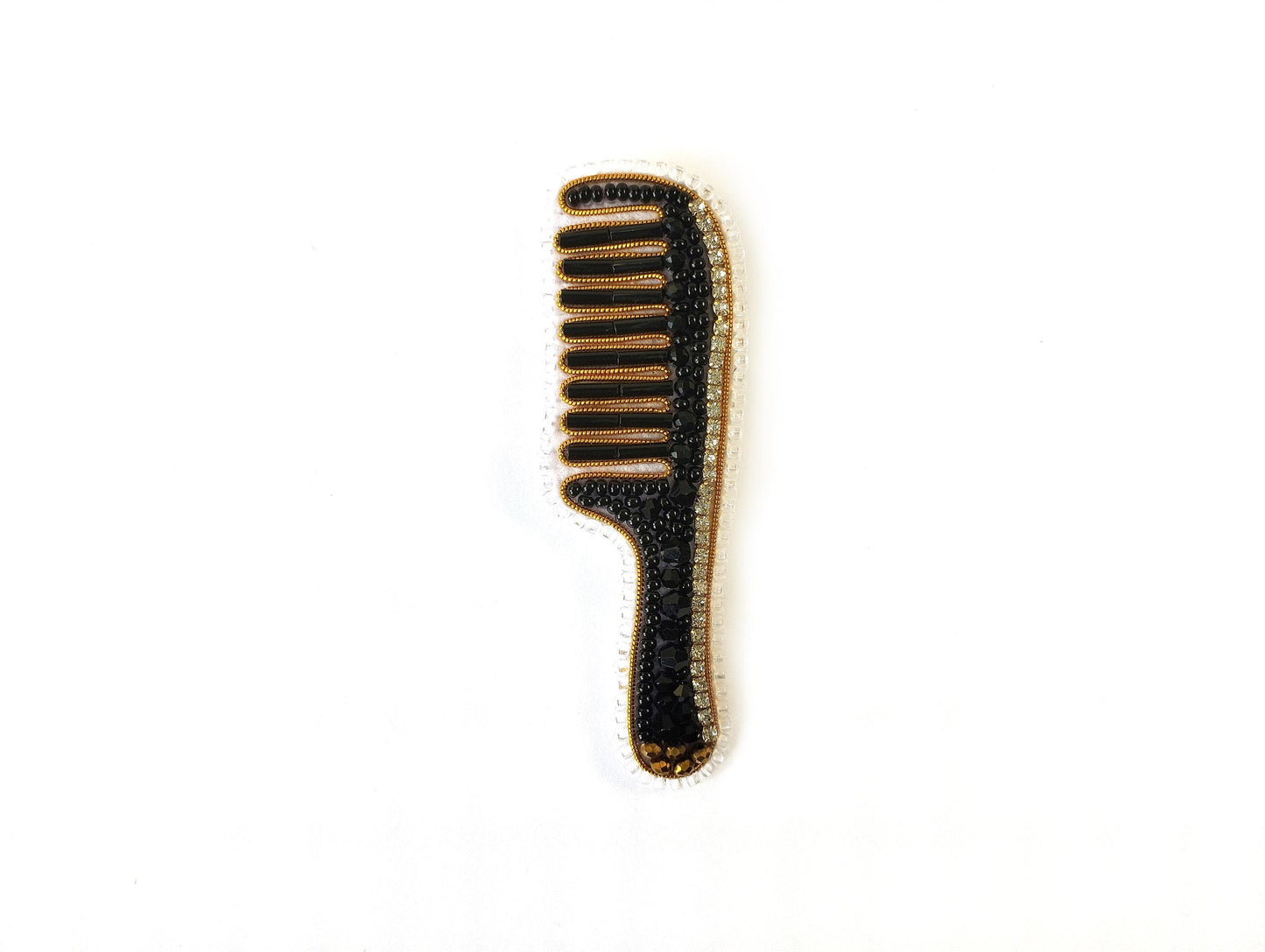 A black comb with gold accents is shown against a white background.