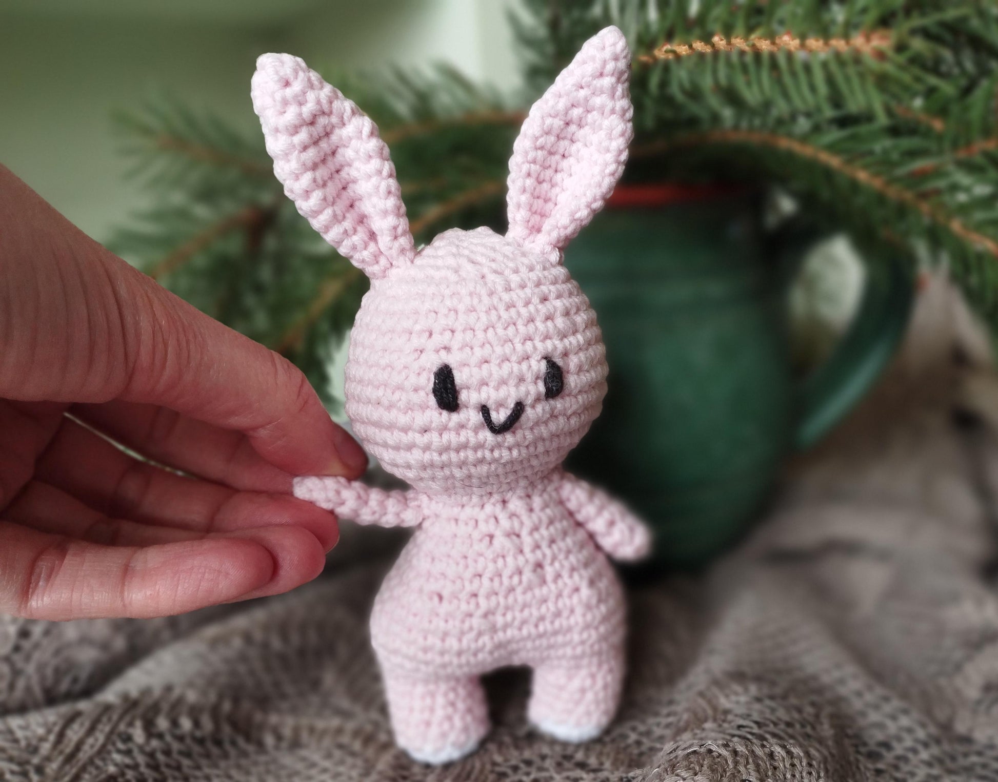 a small crocheted bunny sitting next to a christmas tree