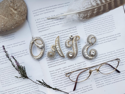 a close-up of a book with text in Russian, a feather, a pair of glasses, and some decorative elements such as pearls and beads.
