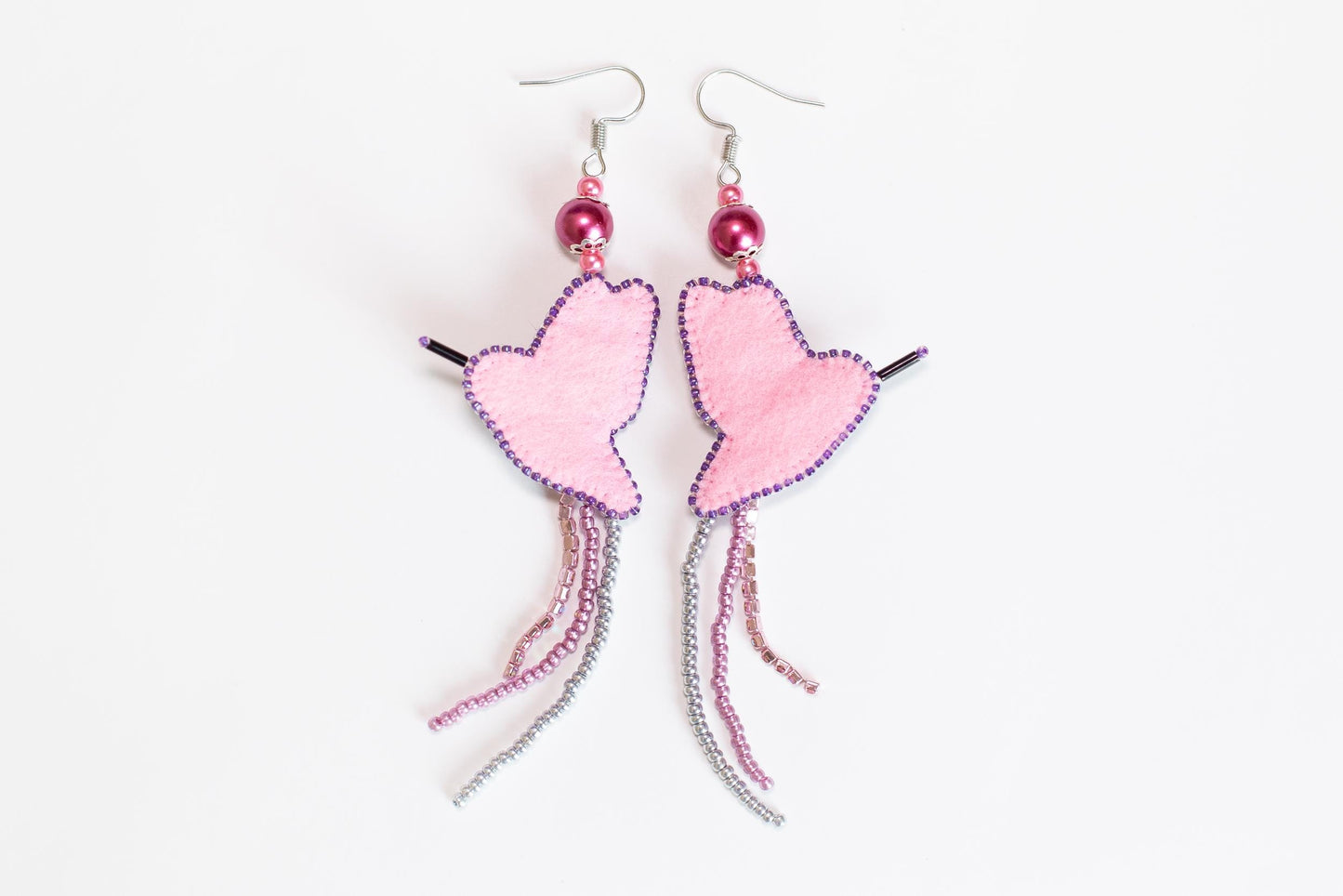 a pair of pink heart shaped earrings on a white background
