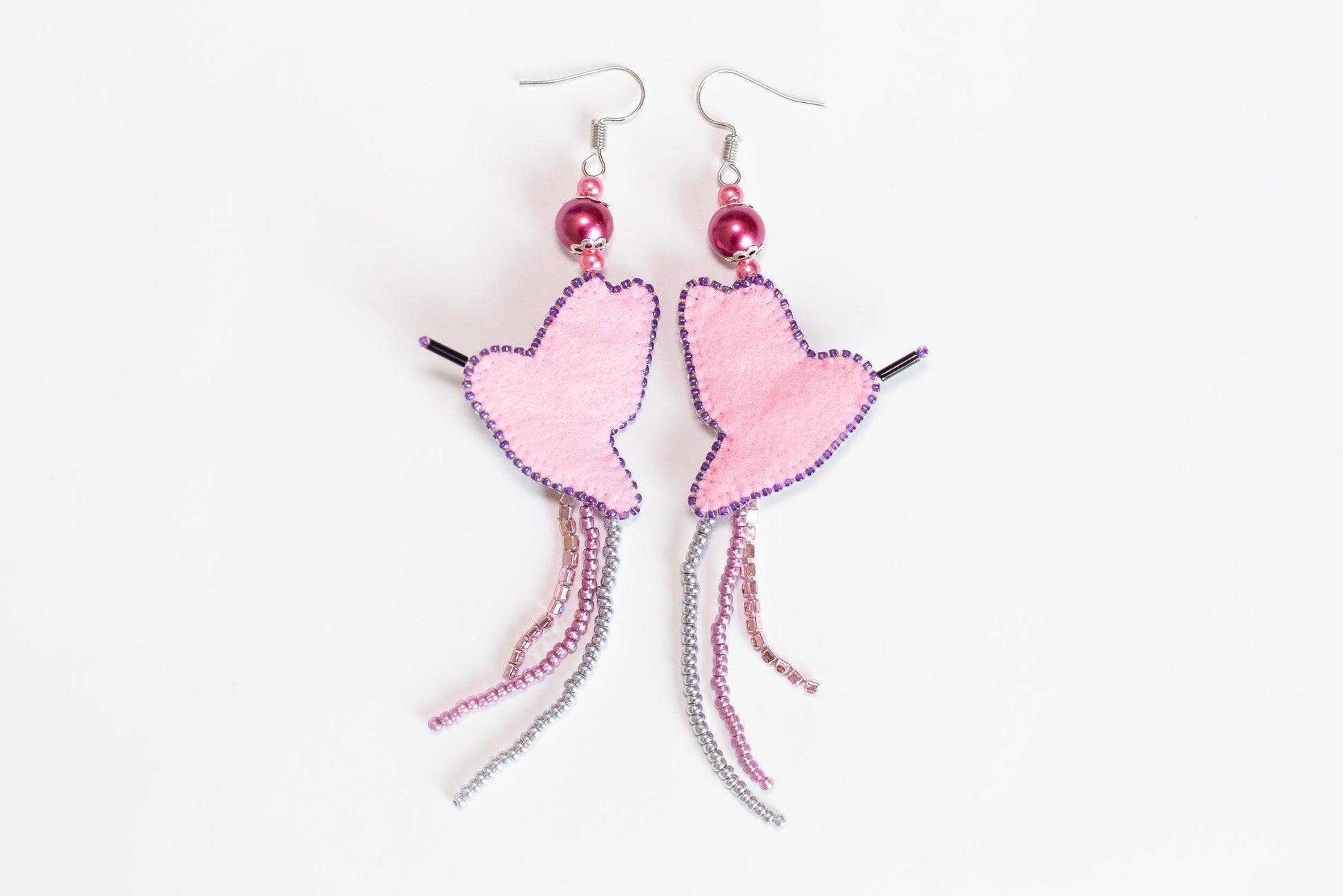 a pair of pink heart shaped earrings on a white background