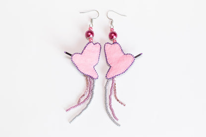 a pair of pink heart shaped earrings on a white background