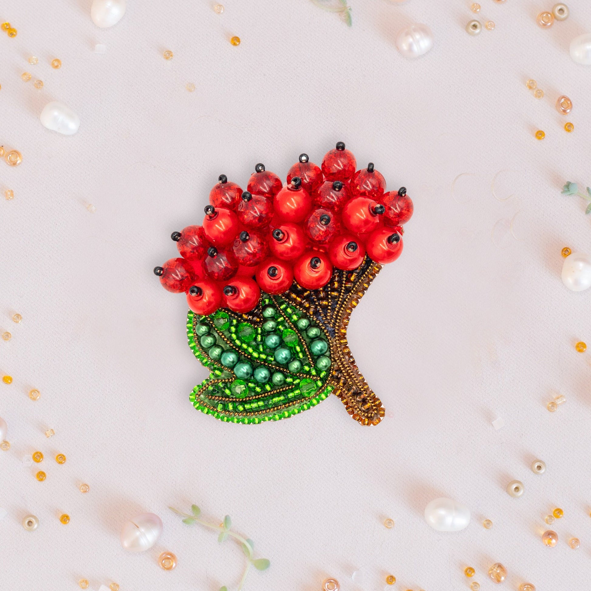 a brooch with red flowers and green leaves