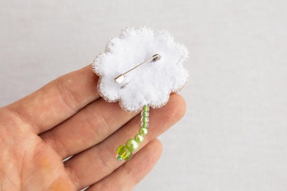 a small brooch with a green bead on it