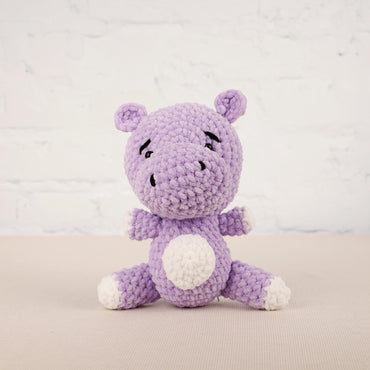 a purple crocheted stuffed animal sitting on a table