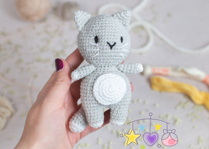 a crocheted cat standing next to a vase of flowers