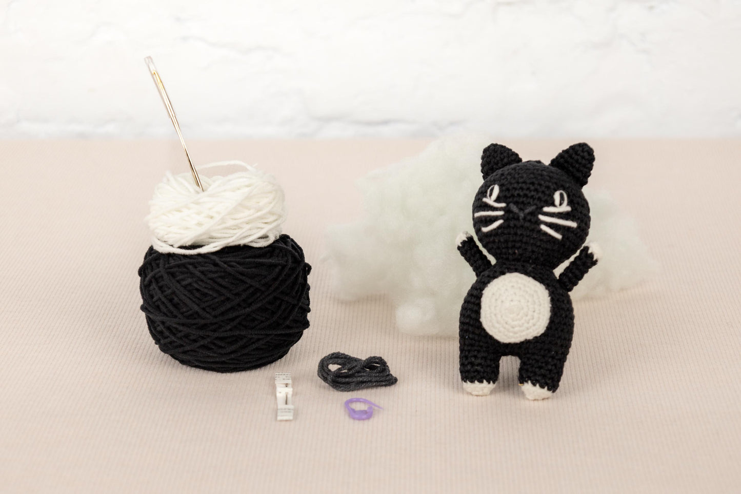 a crocheted cat next to a ball of yarn