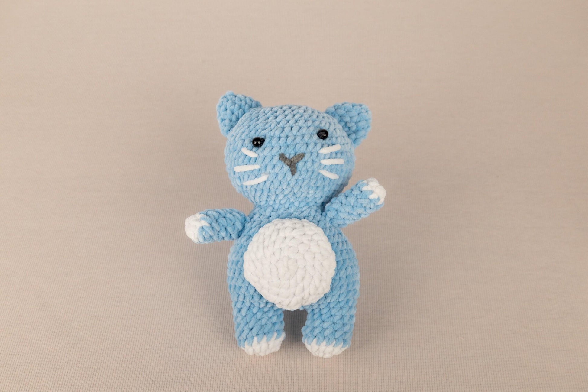 a crocheted blue cat with a white belly