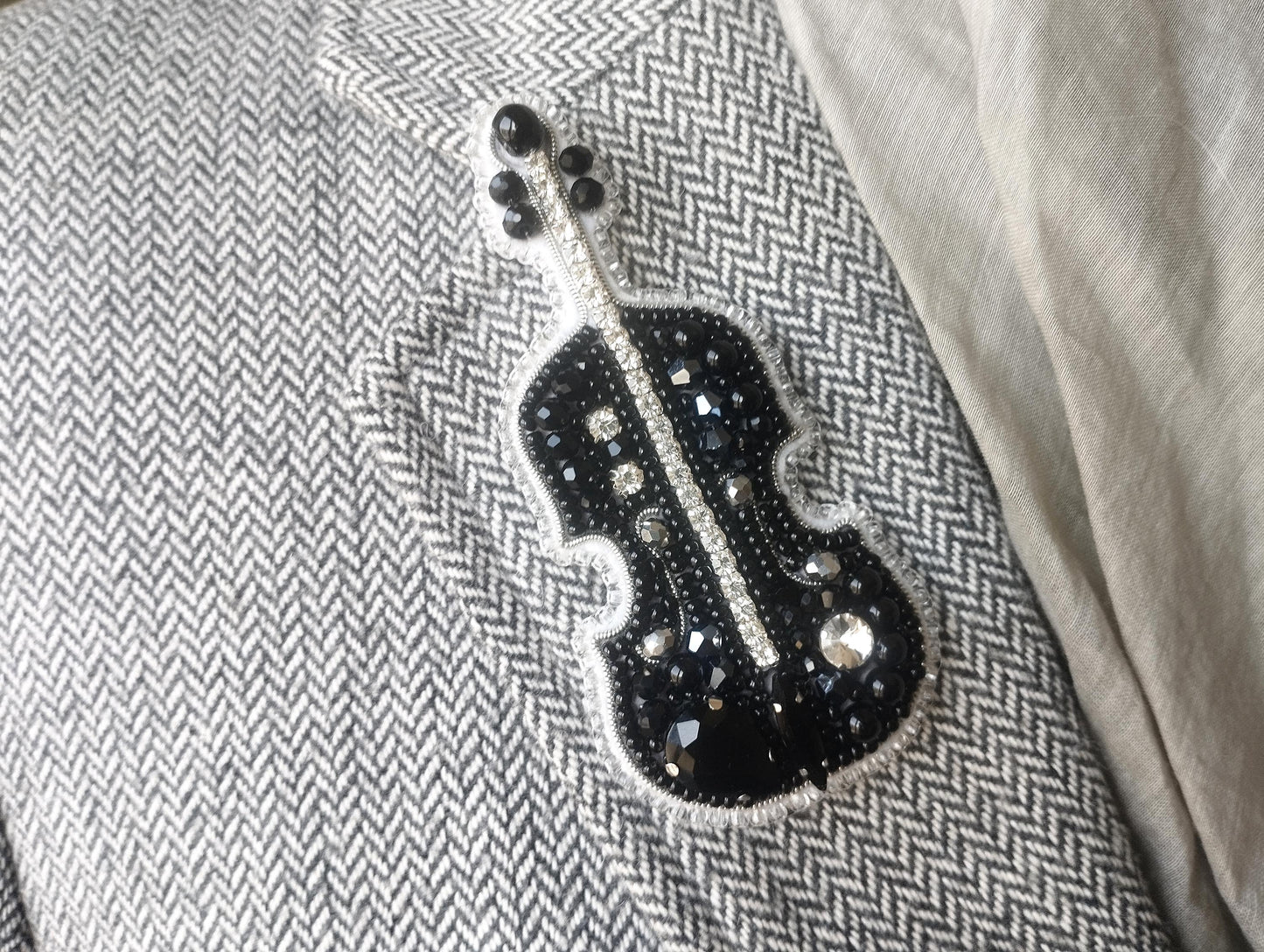 A close-up image of a black and white chevron patterned fabric with a decorative black and silver embellishment resembling a musical instrument, such as a violin or cello.