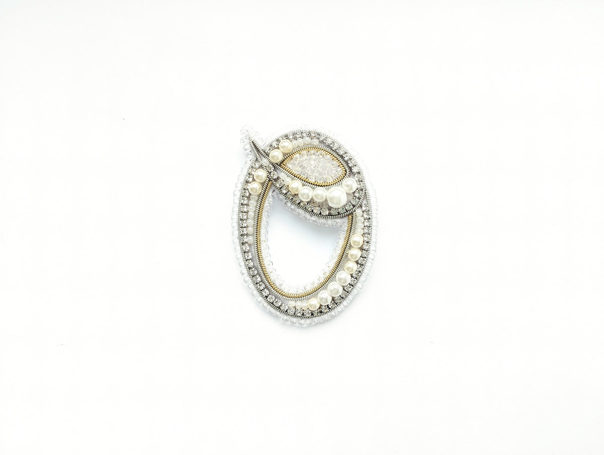 A decorative piece of jewelry, possibly a brooch or pendant, is shown against a white background.