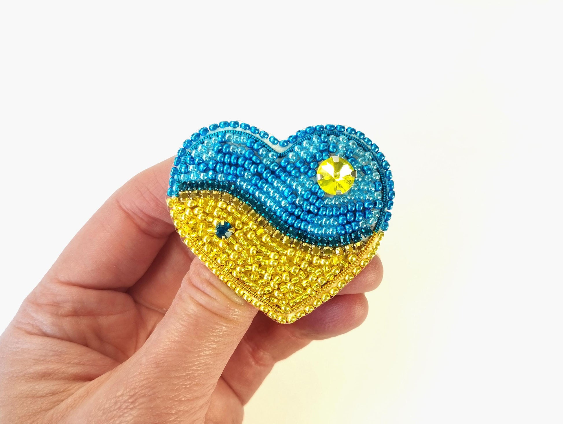 a hand holding a beaded heart shaped object