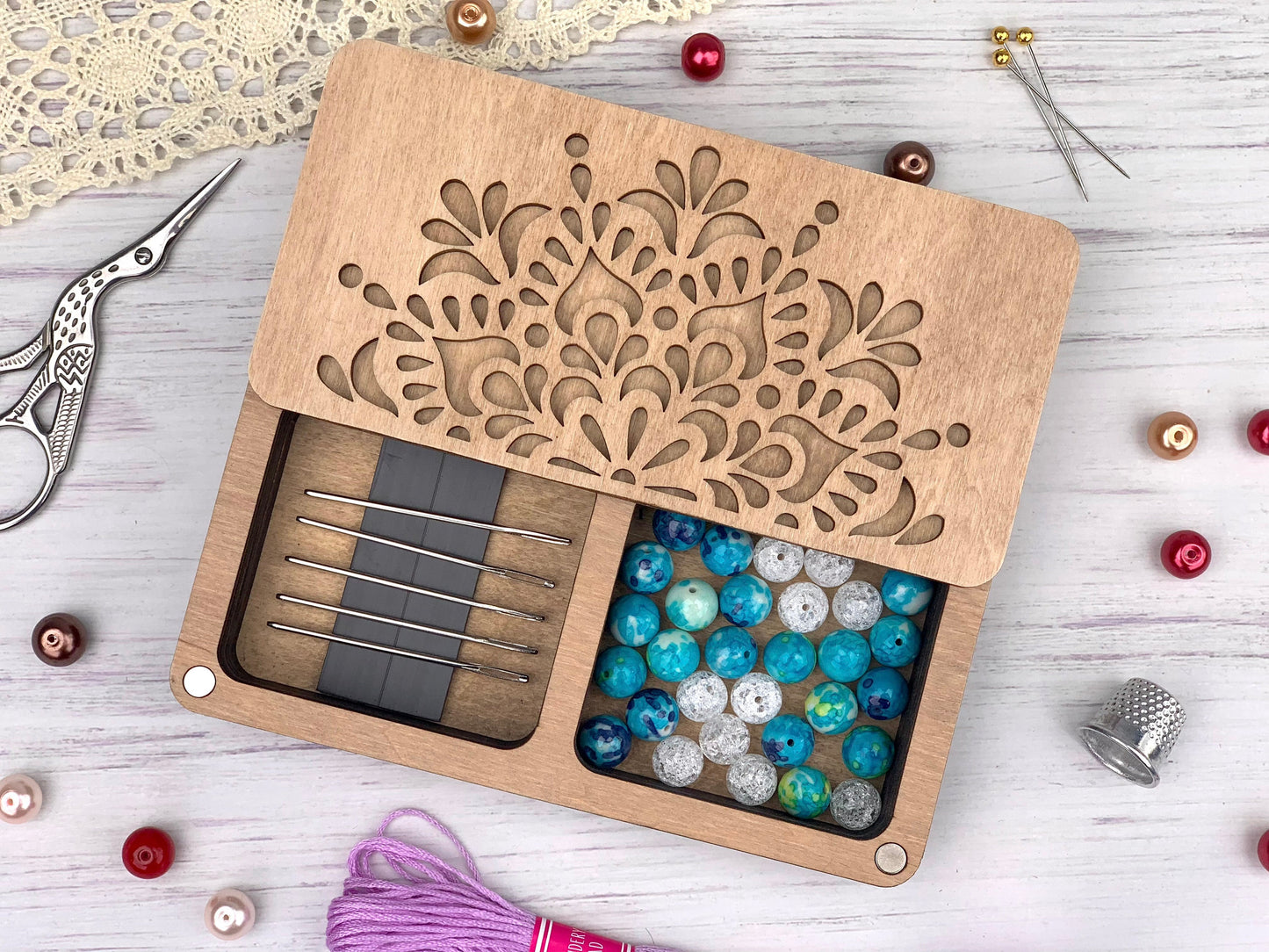 a wooden box filled with beads and a pair of scissors