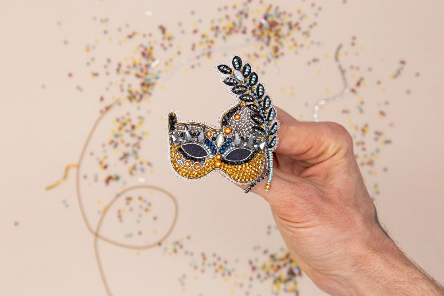 a hand holding a mask in front of a wall