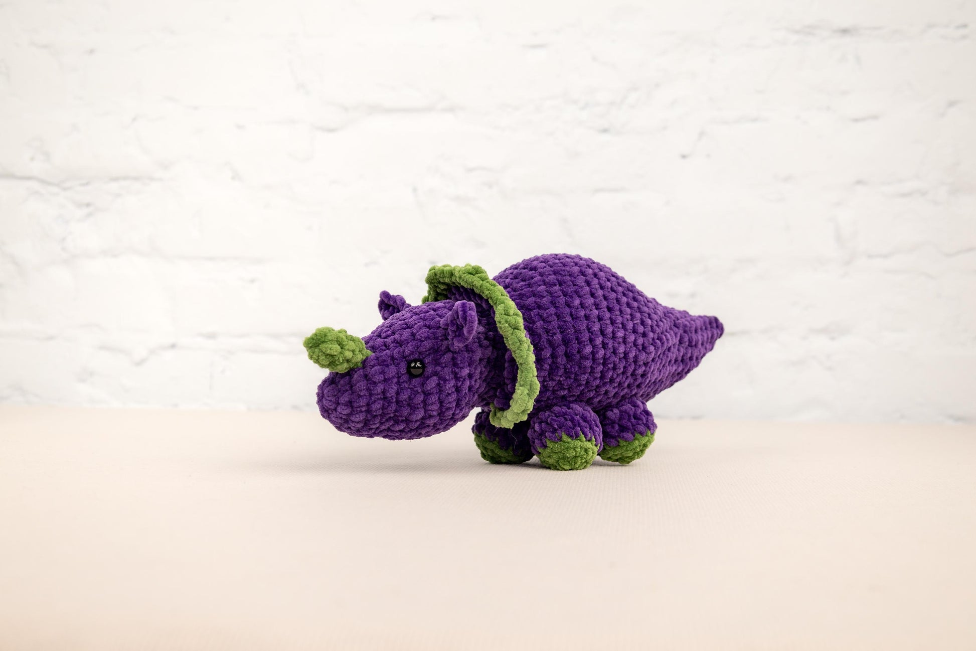 a purple crocheted stuffed animal sitting on a table