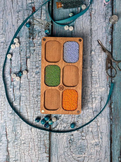 a wooden box filled with beads and a pair of scissors