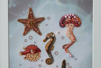 a collection of decorative sea-themed items, including a starfish, a jellyfish, a seahorse, and a fish, all adorned with intricate beading and embellishments.