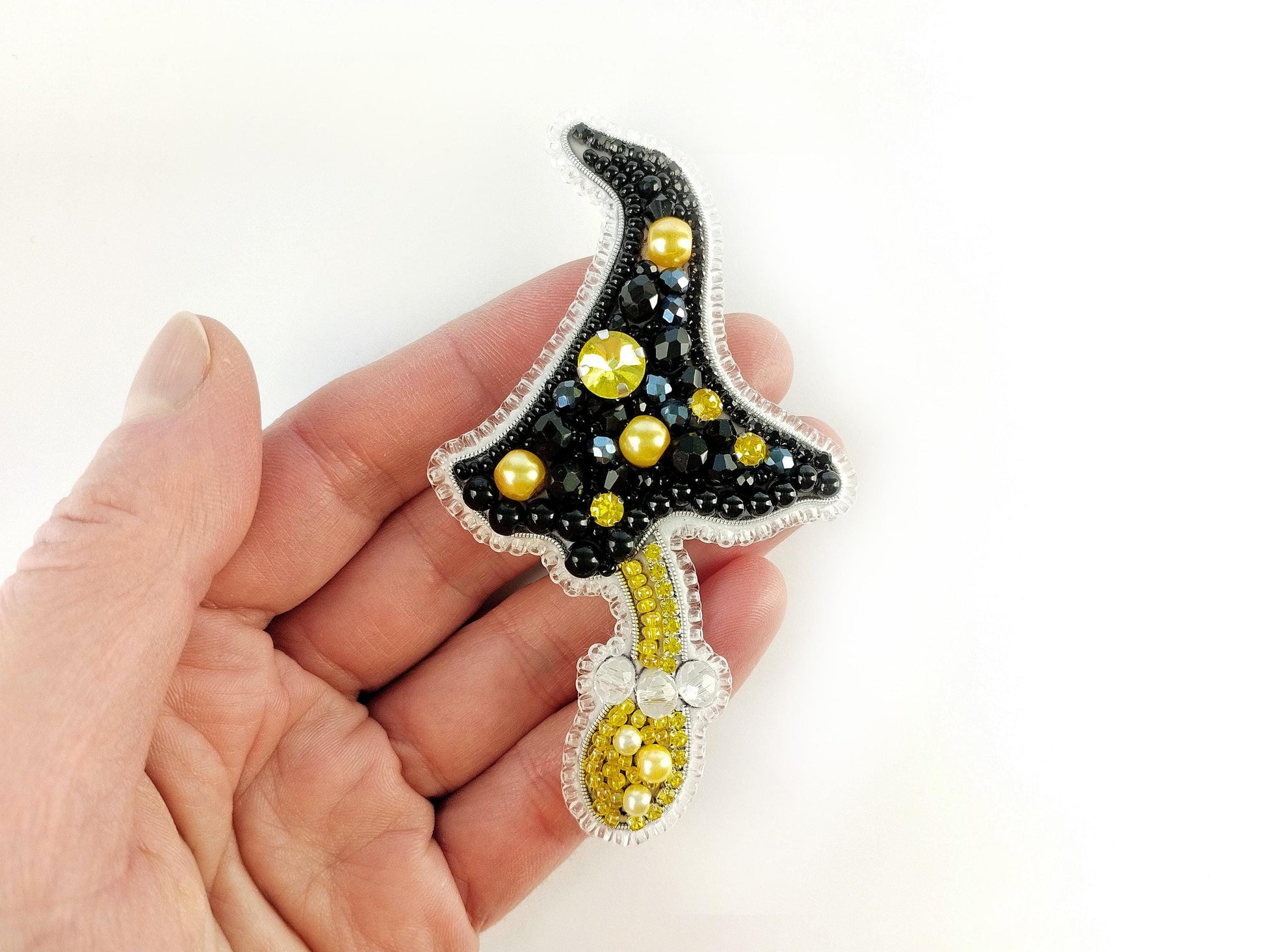 a hand is holding a black and yellow brooch