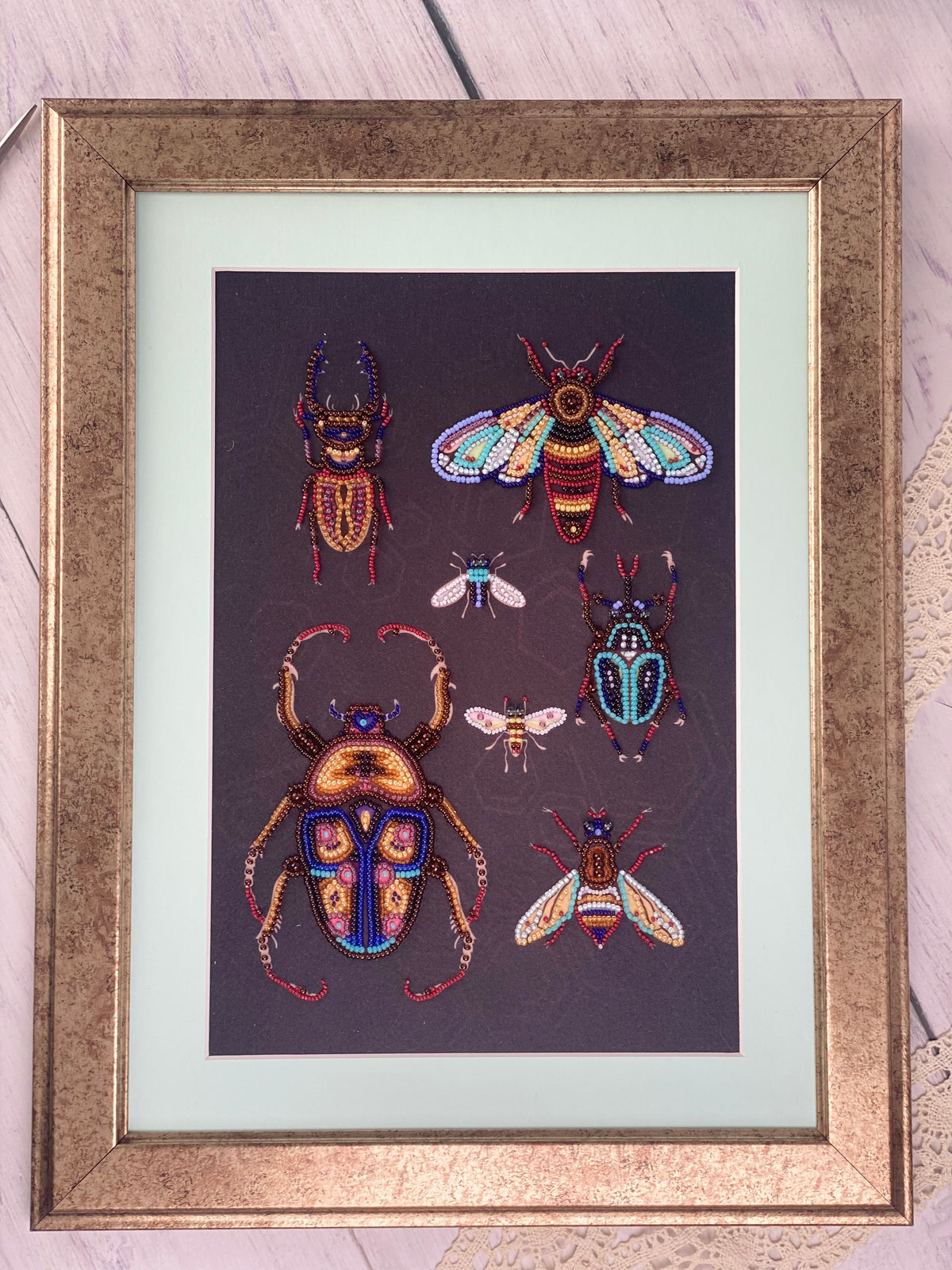 a framed collage of various colorful and detailed insects, including a large dragonfly, a bee, and several other insects, all set against a dark background.
