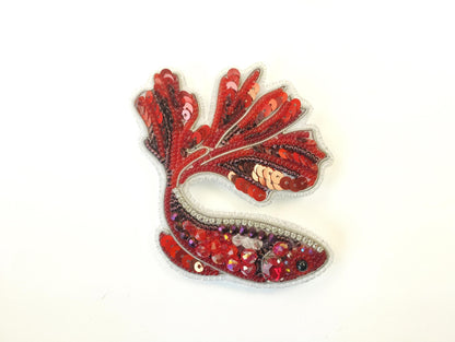 a red and white brooch sitting on top of a white table