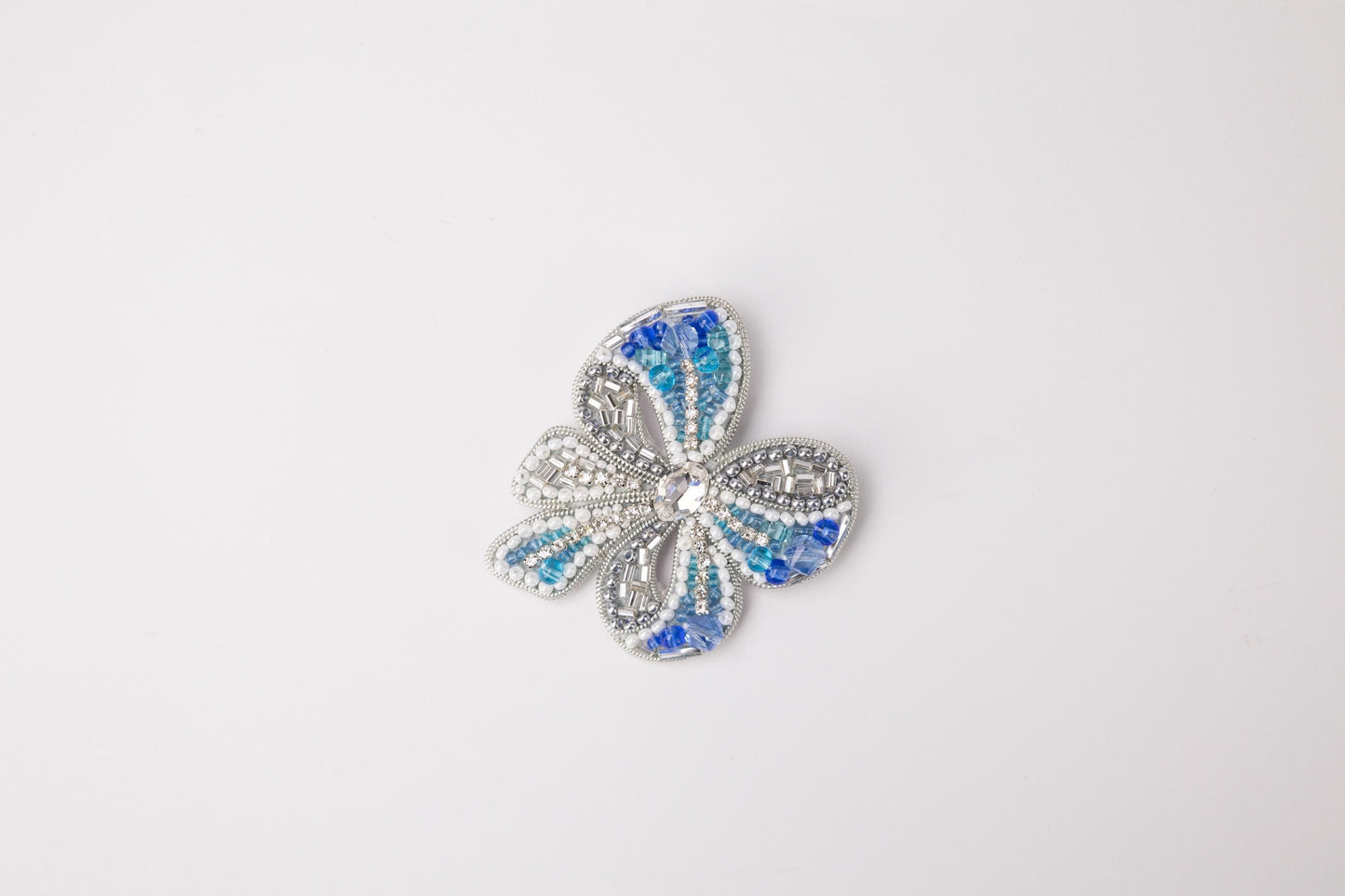 a blue and white flower brooch sitting on top of a white surface