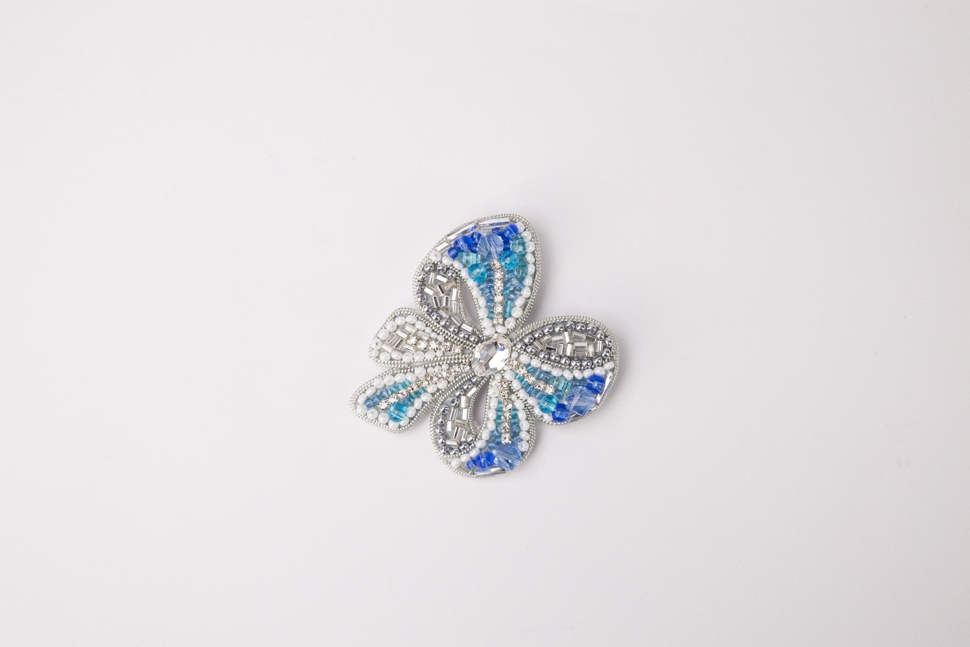 a blue and white flower brooch sitting on top of a white surface