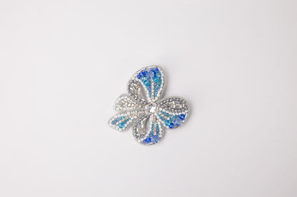 a blue and white flower brooch sitting on top of a white surface