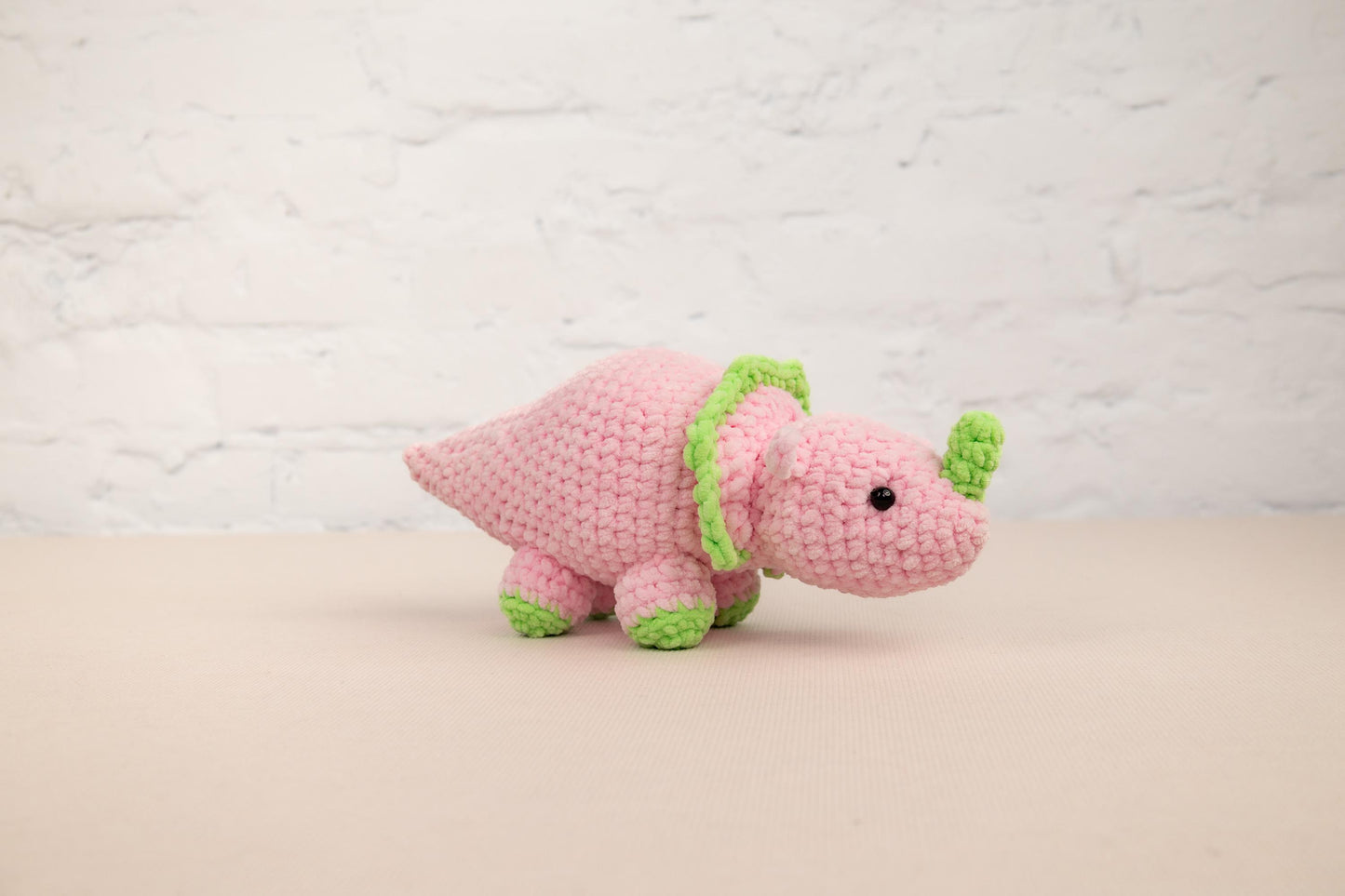 a pink stuffed animal with a green ribbon around its neck