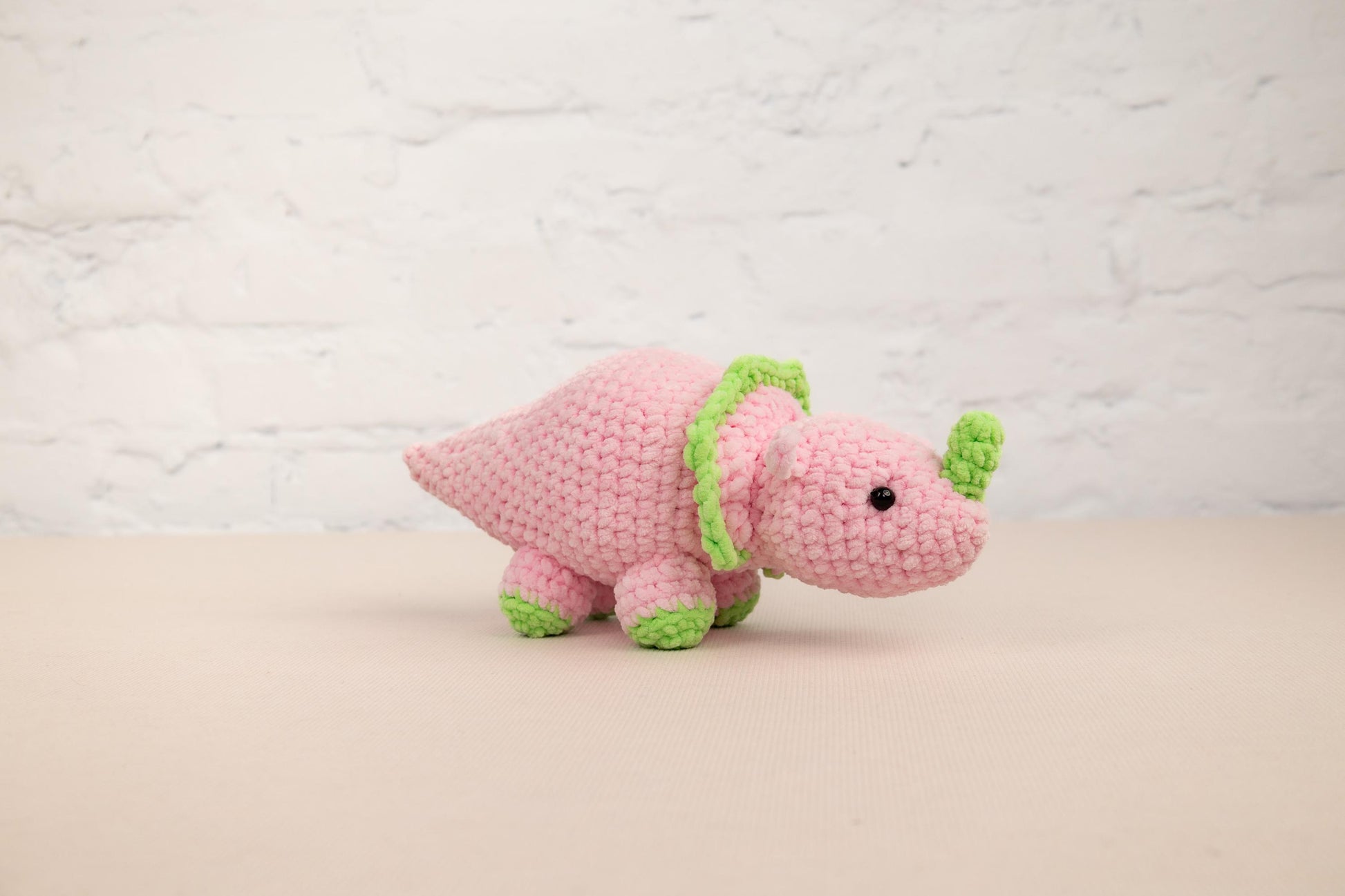 a pink stuffed animal with a green ribbon around its neck