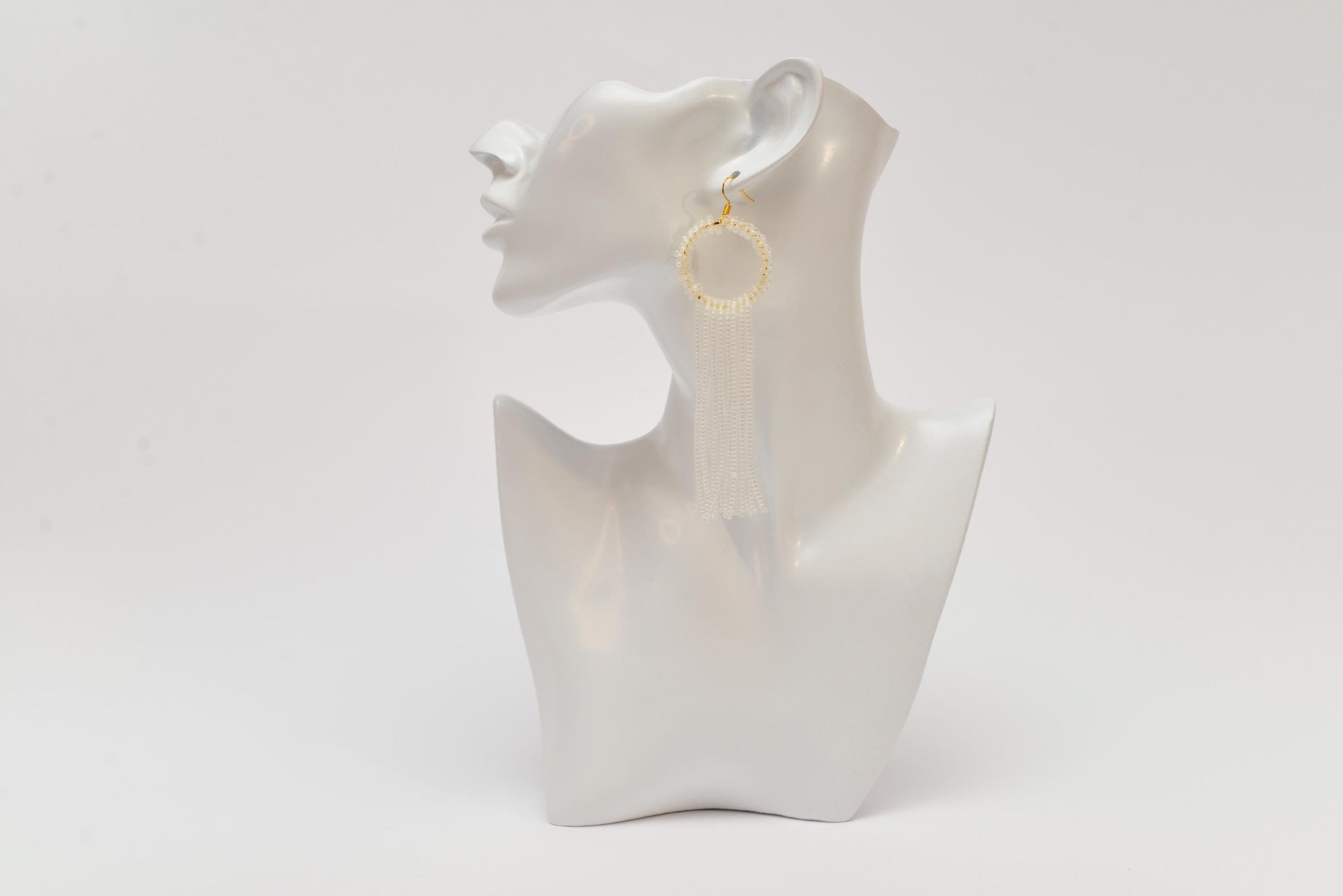 a white mannequin with a pair of earrings on it