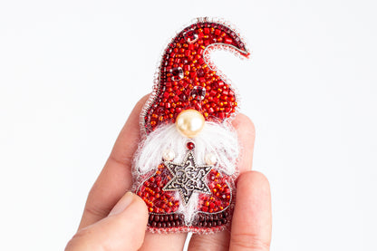 A hand holding a small, intricately designed ornament in red and white colors.